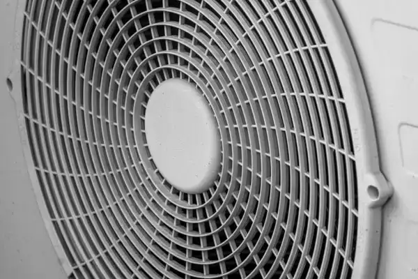 Close-up view of a circular fan grill with a grid pattern, mounted on a flat surface.