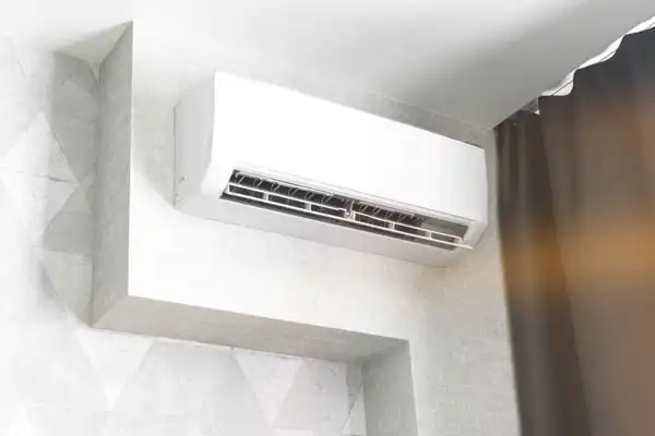 Wall-mounted air conditioner in a room, partially hidden by a dark curtain, with air vents visible.